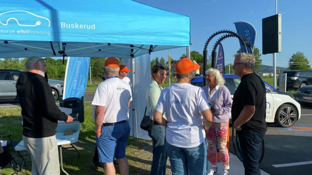 Mennesker på en ladestasjon under et blått telt